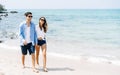 Happy young couple holding hands and laughing walking on beach. Enjoying the summer time by the sea Royalty Free Stock Photo