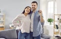 Happy young couple holding a key in their hands standing in a new apartment on moving day. Royalty Free Stock Photo