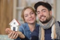 happy young couple holding model house