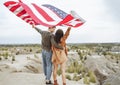 Happy young couple holding a waving American flag in nature. Independence Day, lifestyle, travel concept Royalty Free Stock Photo