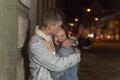 Happy young couple is hugging, evening city background. Guy hugs and kiss his girlfriend. Romantic date on the street Royalty Free Stock Photo