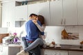 Happy young couple hugging on kitchen. Woman sitting on table.