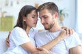 Happy young couple hugging and looking at each other at home interior.