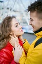 Happy young couple hugging and looking at each other with smile, wearning in bright yellow and red down jackets. Royalty Free Stock Photo