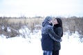 Happy young couple hugging outdoors in a snowy park. Love hugs, family relationships Royalty Free Stock Photo