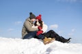 Happy young couple hugging while sitting on the snow. Clear winter weather Royalty Free Stock Photo