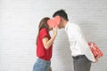 Happy young couple is kissing behind heart on blick wall background Royalty Free Stock Photo