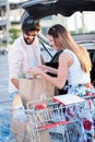 Happy young couple loading grocery bags into a car Royalty Free Stock Photo