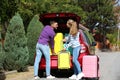 Happy young couple loading suitcases in car trunk Royalty Free Stock Photo