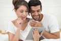 Happy young couple looking a tablet together and laughing while lying on the bed Royalty Free Stock Photo