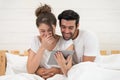 Happy young couple looking a tablet together and laughing while lying on the bed Royalty Free Stock Photo