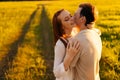 Happy young couple in love with closed eyes hugging, kissing, stroking standing together on green meadow in summer Royalty Free Stock Photo