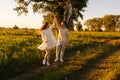 Happy young couple in love dancing together on green meadow in summer evening during sunset with soft sunlight Royalty Free Stock Photo