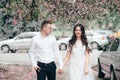 Happy young couple in love enjoys spring day, loving man holding on hands his woman carefree walking at park Royalty Free Stock Photo