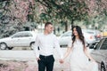 Happy young couple in love enjoys spring day, loving man holding on hands his woman carefree walking at park Royalty Free Stock Photo