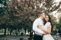 Happy young couple in love enjoys spring day, loving man holding on hands his woman carefree walking at park Royalty Free Stock Photo