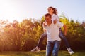 Young couple in love having fun in spring forest. Man rides his girlfriend on back at sunset. Royalty Free Stock Photo