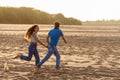 Happy young couple in love is having fun on a wild beach, running towards the sun. Rest, youth, love, lifestyle Royalty Free Stock Photo