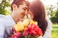 Happy young couple in love hugging with spring flower bouquet outdoors. Man gifted his girlfriend with tulips Royalty Free Stock Photo