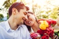 Happy young couple in love hugging with spring flower bouquet outdoors. Man gifted his girlfriend with tulips Royalty Free Stock Photo