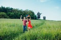 Happy young couple in love runing a kite on the field. Two, man and woman smiling and resting in the country side