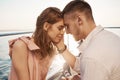 Happy young couple in love smiling and enjoying boat trip on the sea. Romance and vacation concept. Boyfriend tenderly Royalty Free Stock Photo