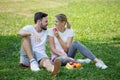 Happy young couple loving fitness in sportswear relaxing at park eating apple together in morning time. sport people sitting Royalty Free Stock Photo