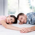 Happy young couple, lying on the floor, look at each other and dream of furniture for a new apartment. Mock up Royalty Free Stock Photo