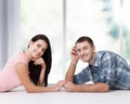 Happy young couple, lying on the floor, look at each other and dream of furniture for a new apartment. Mock up Royalty Free Stock Photo