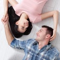 Happy young couple, lying on the floor, look at each other and dream of furniture for a new apartment. Mock up Royalty Free Stock Photo