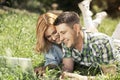 Happy young couple lying on the grass, looking at laptop and smiling. Relationship concept. Royalty Free Stock Photo