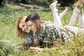 Happy young couple lying on the grass, looking at laptop and smiling. Relationship and learning concept. Royalty Free Stock Photo