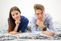 Happy young couple lying together on the bed and looking at camera. Royalty Free Stock Photo