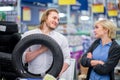 Happy young couple make choice with car tires in shopping mall Royalty Free Stock Photo