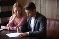 Happy young couple making deal, husband signing contract at meeting