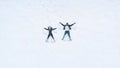 Happy young couple making snow angels. High angle