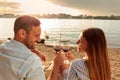 Happy young couple making a toast with red wine. Enjoying picnic at the beach