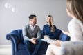 Happy young couple making up at therapy session with psychologist