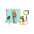 Happy young couple, man and pregnant woman in photo studio. Photographer sitting on his knee and taking family picture Royalty Free Stock Photo