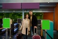 Happy young couple, man and woman, business partners standing with luggage and suitcases at the check-in counter, passing customs Royalty Free Stock Photo