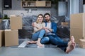 Happy young couple man and woman at home sitting on sofa in new rented apartment, near cardboard boxes Royalty Free Stock Photo