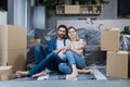 Happy young couple man and woman at home sitting on sofa in new rented apartment, near cardboard boxes Royalty Free Stock Photo