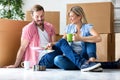 Happy young couple moving in new home unpacking boxes and choosing color Royalty Free Stock Photo