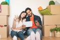 Happy young couple moving in new property house - Young lovers having fun using tablet shopping online sitting next carton box Royalty Free Stock Photo