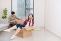 Happy young couple moving in their new apartment, having fun and riding in cardboard boxes at new home