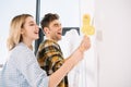Young couple painting white wall in yellow with paint rollers Royalty Free Stock Photo