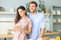 Happy young couple in pajamas in kitchen at home looking away from the camera, morning Royalty Free Stock Photo