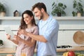 Happy young couple in pajamas watching online content in a didital tablet and smiling in kitchen at home Royalty Free Stock Photo