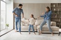 Happy young couple parents dancing with small daughter.