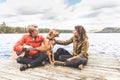 Happy young couple playing with dog on a dock Royalty Free Stock Photo